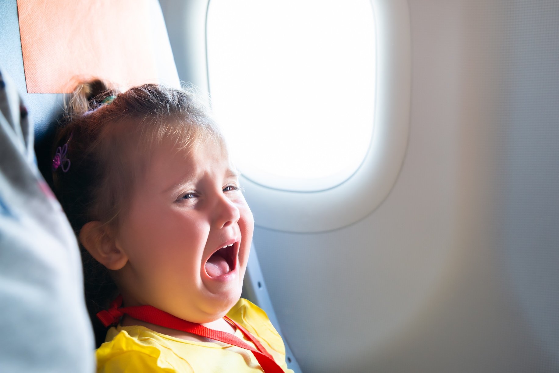 A toddler is seen crying while riding an airplane.