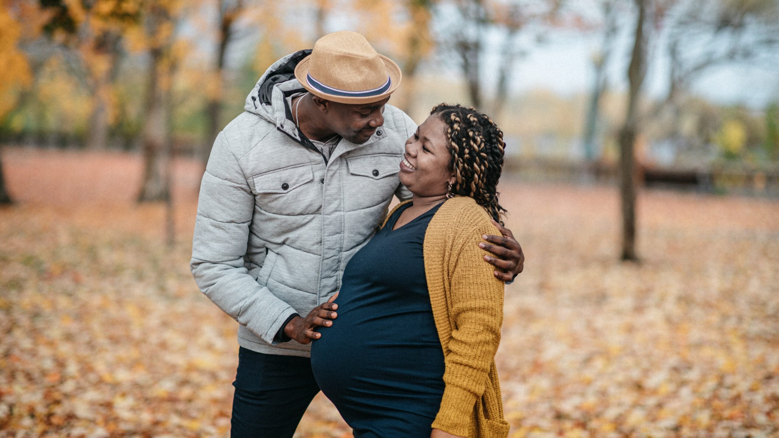 pregnant person and their partner outside in the fall