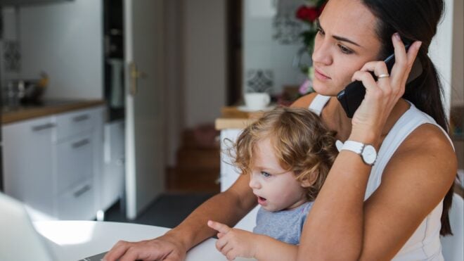 mom on phone with child on her lap