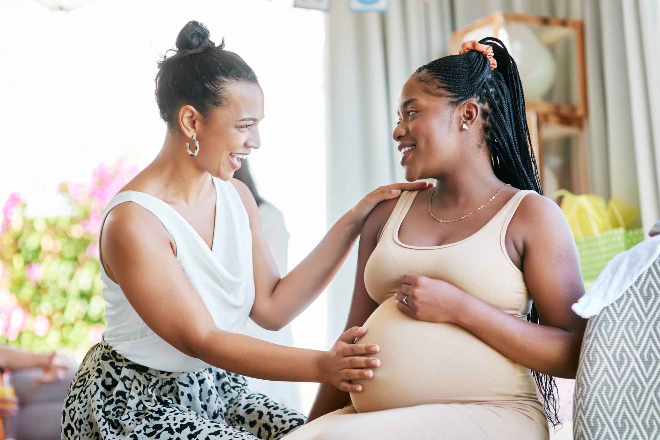 Shot of a woman touching her friends belly during her baby shower