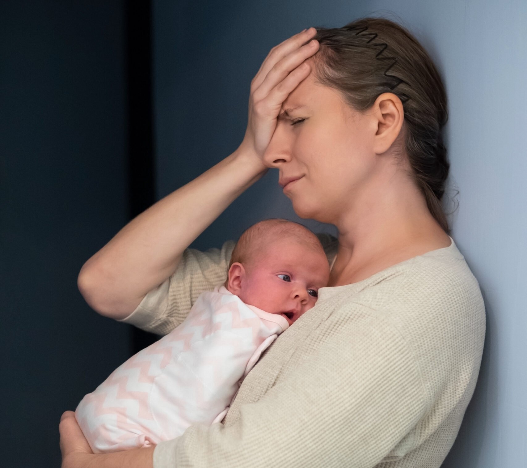 Caucasian mother with baby suffering from post natal depression, postpartum preeclampsia headache