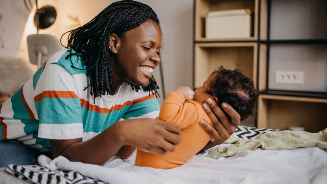Shot of a young woman playing with her adorable baby on the bed at home
