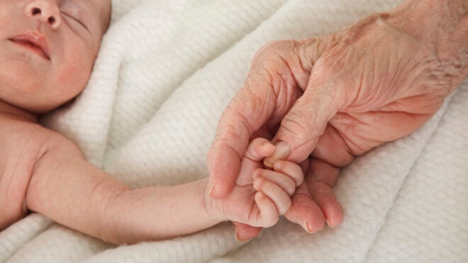 aging parents, sleeping baby holding great grandmother's hand