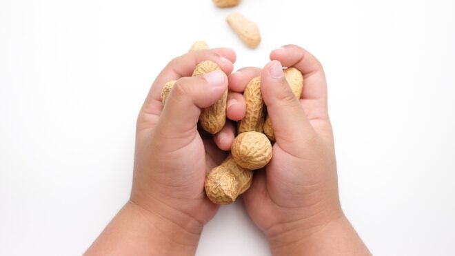 A baby holding peanuts