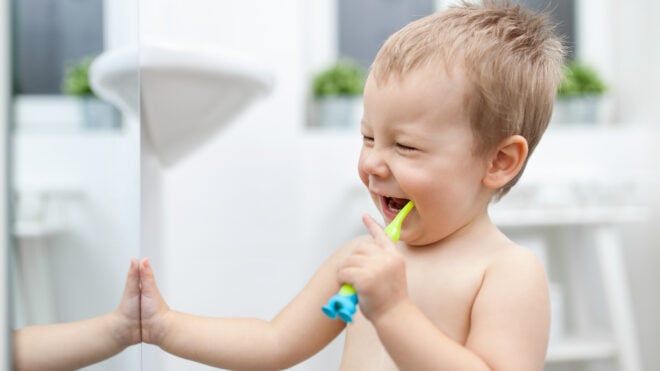 Happy toddler boy brushing his teeth