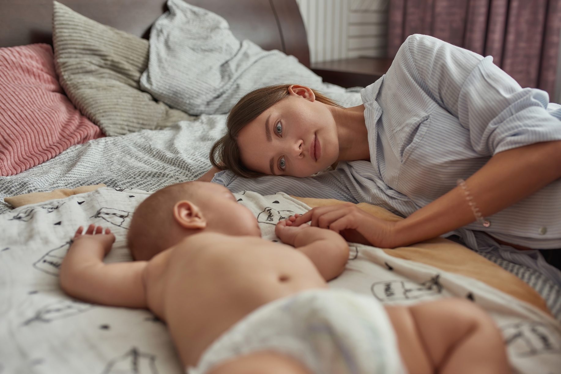 Mom and baby laying in bed, co-sleeping.
